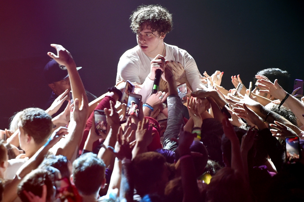 Jack Harlow performs in a white shirt surrounded by fans. 