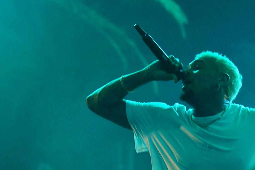 Chris Brown on stage in a white shirt.