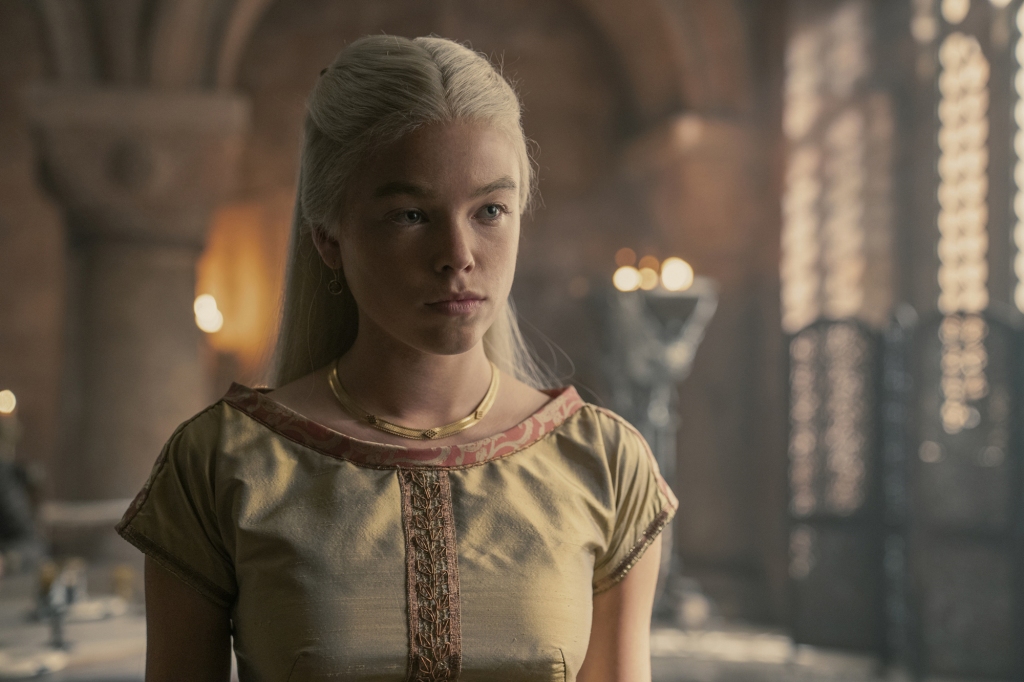 Milly Alcock as Princess Rhaenyra Targaryen in "House of the Dragon" standing in a room with a dress on. 