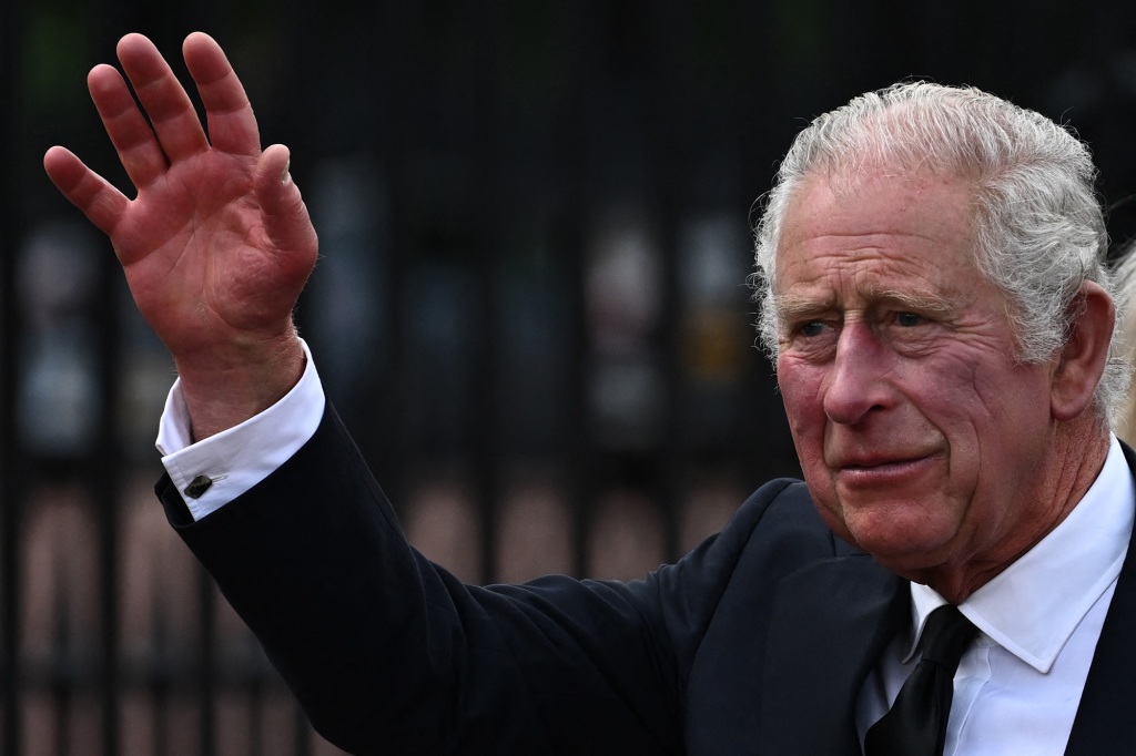 Britain's King Charles III waves as he walks into Buckingham Palace after the death of his mother, Queen Elizabeth II.
